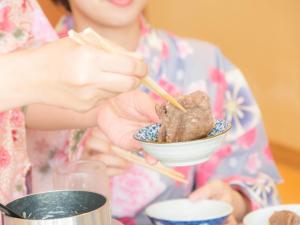 a woman spooning food into a bowl on a table at Hotel Areaone Hiroshima Wing in Higashihiroshima