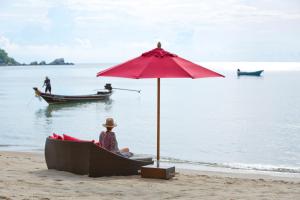 a person sitting in a boat under an umbrella on the beach at Anantara Rasananda Koh Phangan Villas in Thong Nai Pan Noi