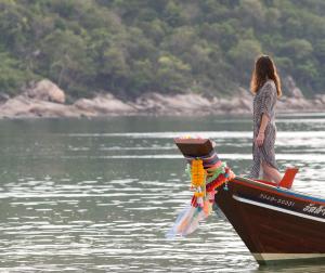 a woman standing on the front of a boat in the water at Anantara Rasananda Koh Phangan Villas in Thong Nai Pan Noi
