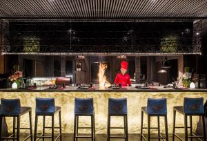 a chef standing behind a kitchen counter with a fire at Anantara Rasananda Koh Phangan Villas in Thong Nai Pan Noi