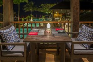 a wooden table with two chairs and a lamp on a patio at Anantara Rasananda Koh Phangan Villas in Thong Nai Pan Noi