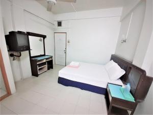 een kleine slaapkamer met een bed en een televisie bij Singapore Hotel in Hat Yai