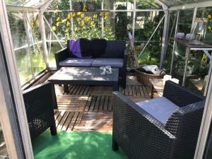 a screened porch with a couch and chairs and a table at Det Bette Hus in Hjørring