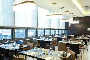 un ristorante con tavoli, sedie e finestre di Ramada by Wyndham Daejeon a Daejeon