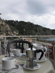 einen Tisch mit zwei Tassen und einen Wasserkocher auf dem Balkon in der Unterkunft B&B Agon in Taormina