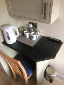 una encimera de cocina con cafetera y tazas. en Private en-suite guestroom Ruthin en Ruthin