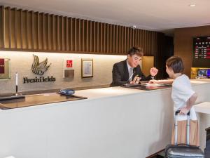 un hombre y una mujer parados en un mostrador de recepción en Freshfields Hotel, en Wuri