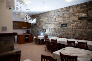 Guest House Lŭgŭt في Berievo: غرفة طعام بجدار حجري وطاولات وكراسي