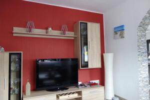 un soggiorno con TV su una parete rossa di Ferienhaus Rurperle a Nideggen