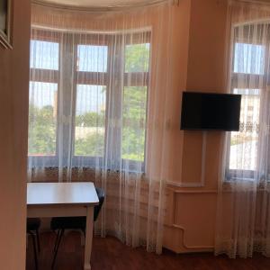 キスロヴォツクにあるSemeiniy Otdihの窓2つ、デスク、テレビが備わる客室です。