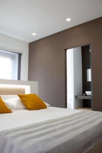 ein Schlafzimmer mit einem großen weißen Bett mit gelben Kissen in der Unterkunft Xenia, B&B Soverato in Soverato Marina