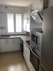 uma cozinha com electrodomésticos de aço inoxidável e armários brancos em Apartamento Felisa em Arcos de la Frontera