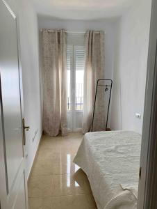 a white bedroom with a bed and a window at Apartamento Felisa in Arcos de la Frontera