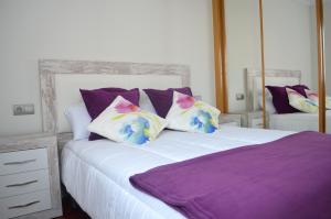 a bedroom with a bed with purple and white pillows at Piso Céntrico y Moderno in Gijón
