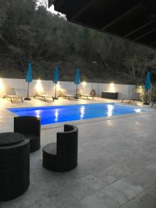 a swimming pool at night with chairs and umbrellas at Grande maison avec piscine in Porto-Vecchio