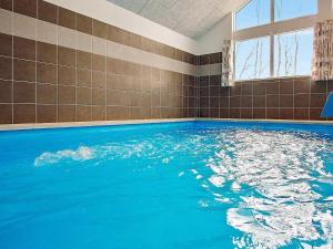 a large swimming pool with blue water in a room at 16 person holiday home in Hasselberg in Kappeln