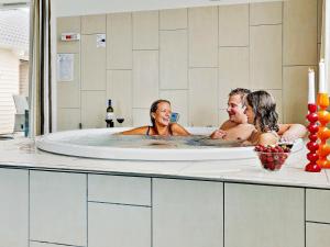 3 personas en una bañera de hidromasaje en un baño en 22 person holiday home in Bogense, en Bogense