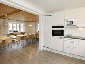 a kitchen with white cabinets and a table and chairs at 14 person holiday home in Bl vand in Ho