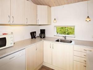 a kitchen with white cabinets and a sink and a microwave at 6 person holiday home in Tarm in Tarm