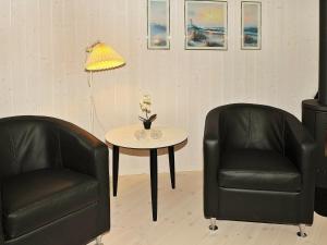 ヘンネ・ストランドにある8 person holiday home in Henneの黒革の椅子2脚、テーブル(ランプ付)