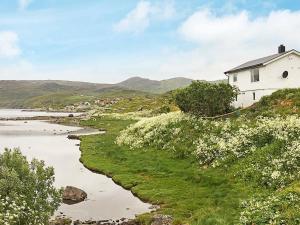 a white house on a hill next to a river at Holiday Home Breivikbotn in Vatna