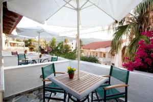 a table and chairs on a balcony with an umbrella at Notis Hotel in Samos