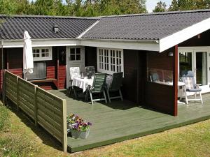 una terraza con mesa y sillas en una casa en Three-Bedroom Holiday home in Ålbæk 48 en Ålbæk