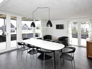 8 person holiday home in R m في رومو كيركيبي: غرفة طعام مع طاولة بيضاء وكراسي سوداء