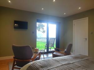 a bedroom with a bed and chairs and a window at Open acres accommodation and airport parking in Bristol