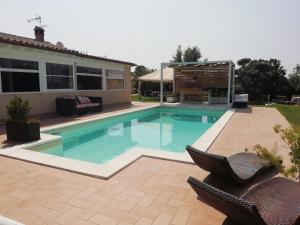a swimming pool in a yard with two chairs and a house at Corte Franca La Nuova Era in Tragliata