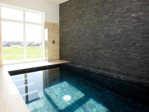 a swimming pool in a room with a brick wall at 18 person holiday home in Løkken-By Traum in Løkken
