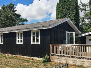 斯泰厄的住宿－5 person holiday home in Stege，一间黑色的房子,设有白色的窗户和栅栏