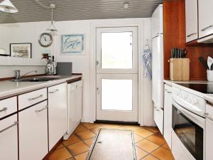 フルシグにある6 person holiday home in Skagenの白いキャビネットとドア付きのキッチン