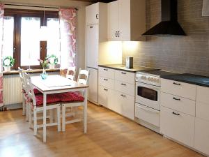 kuchnia z białymi szafkami i stołem z krzesłami w obiekcie Five-Bedroom Holiday home in Hova 2 w mieście Berga