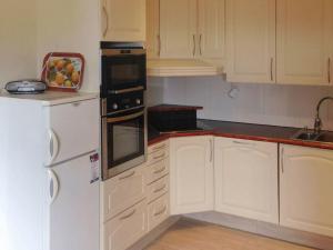 una cocina con armarios blancos y un bol de fruta en la barra en Holiday Home Breivikbotn, en Vatna