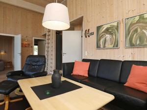 a living room with a black couch and a table at 8 person holiday home in Ulfborg in Fjand Gårde