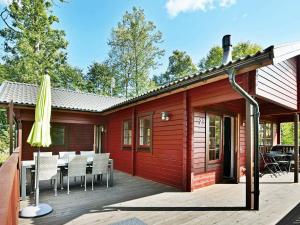 Cabaña de madera con terraza con mesa y sillas en Three-Bedroom Holiday home in Hästveda, en Hästveda