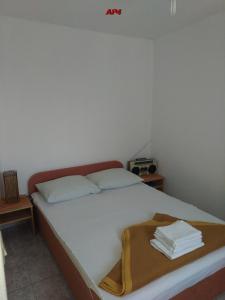 a bed with white sheets and a brown bag on it at Apartments Šudić in Njivice