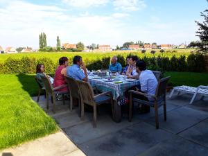 een groep mensen die rond een tafel in een tuin zitten bij vakantiewoning Het Boomkwekerijhuis in Zonnebeke