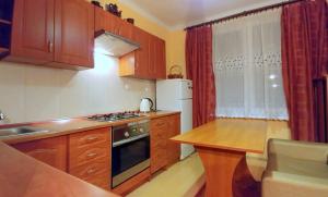 a small kitchen with wooden cabinets and a table in it at Apartament TwojaNoc in Mielec