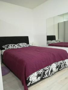 a bedroom with a bed with a purple blanket at DRENO Apartman in Zagreb