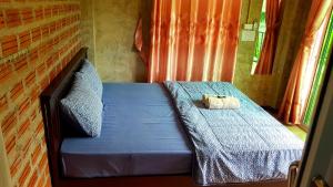 a small bed with a blue comforter and a bag on it at ฮ้างนาตาจันทร์ in Pua