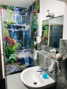 a bathroom with a sink and a waterfall mural at City Pension in Plettenberg