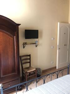 ein Schlafzimmer mit einem Bett, einem Stuhl und einem TV in der Unterkunft Alloggi per uso turistico A&M in Acquapendente