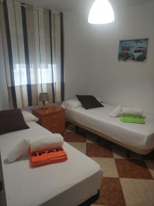Habitación con 2 camas, mesa y lámpara. en CASA CARMEN 20 en Málaga