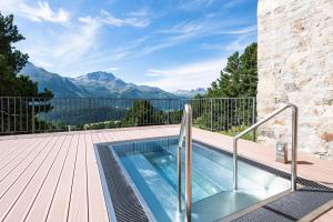 a swimming pool on a deck with a view of mountains at Berghotel Randolins in St. Moritz