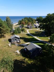 an aerial view of a village with a house and the ocean at Camping Noras in Mērsrags