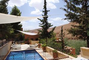 a villa with a swimming pool with a mountain in the background at Auberge Chez Pierre in Boumalne Dades