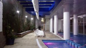 una piscina en un edificio con sillas blancas en Euromarina Dos Reñaca, en Viña del Mar