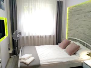1 dormitorio con 1 cama blanca con 2 almohadas y ventana en Apartament UnoPuro w centrum Giżycka, en Giżycko